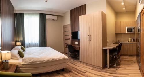 a bedroom with a bed and a desk and a kitchen at Metropolis Apartamenty Centrum in Kalisz