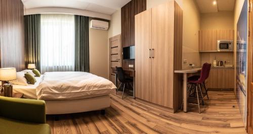 a bedroom with a bed and a desk and a kitchen at Metropolis Apartamenty Centrum in Kalisz