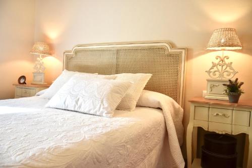 a bedroom with a white bed with two lamps at Villa Miranda in El Rompido