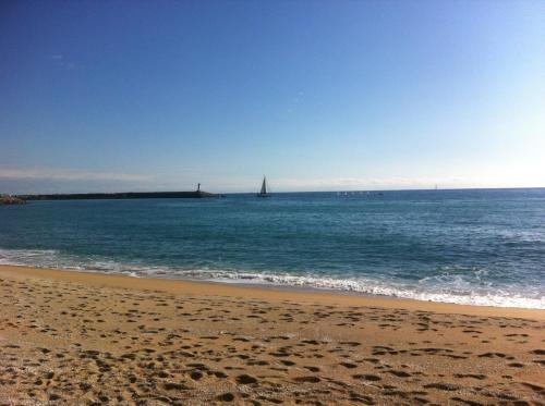 a beach with a sail boat in the water at Sa Voga Hotel & Spa in Arenys de Mar