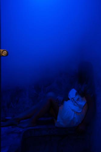 a woman laying on a bed in a blue room at Ξενώνας Οντάς και Spa in Arachova