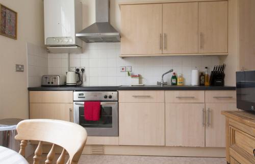 a kitchen with wooden cabinets and a stove top oven at Dale Street Apartments Suite in Leamington Spa