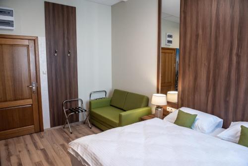a bedroom with a bed and a green chair at Metropolis Apartamenty Centrum in Kalisz