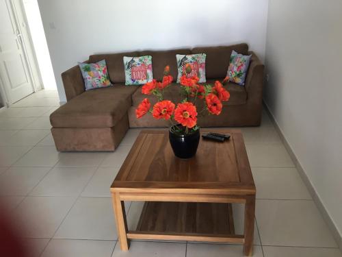 a living room with a couch and a table with red flowers at 3 Rue du Bois d’inde Anse-Mitan in Les Trois-Îlets