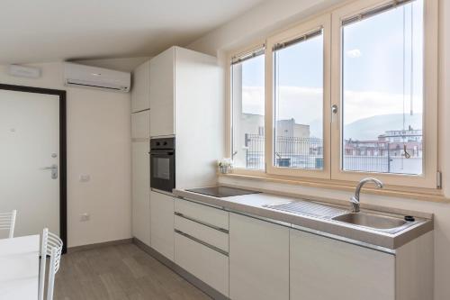 eine Küche mit weißen Schränken, einem Waschbecken und 2 Fenstern in der Unterkunft Il Nido - Miniattico panoramico by AppartamentiPetrucci in Foligno