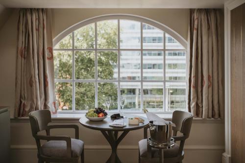 a table and chairs in front of a large window at The LaLit London in London