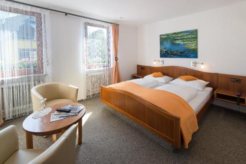 ein Schlafzimmer mit einem großen Bett, einem Tisch und einem Stuhl in der Unterkunft Hotel Weinhaus Weis in Leiwen