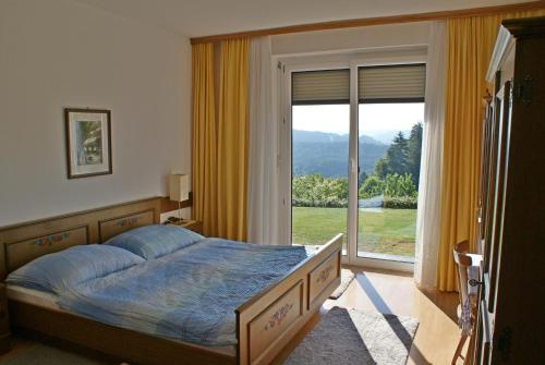 a bedroom with a bed and a large window at Haus Panorama in Keutschach am See