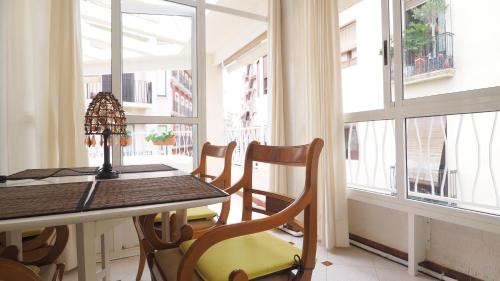 - une table à manger et des chaises dans une pièce avec fenêtres dans l'établissement Precioso Atico, à Alicante