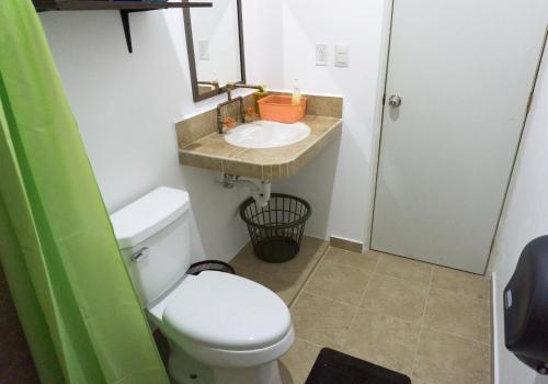 a bathroom with a white toilet and a sink at Hacienda bambú in Bacalar