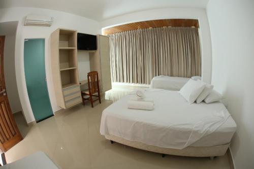 a bedroom with a large white bed and a chair at Hotel Ed. Carolmilla in Valença