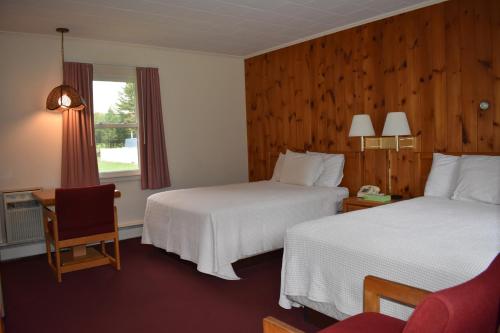 ein Hotelzimmer mit 2 Betten und einem Stuhl in der Unterkunft Country Club Motel in Old Forge