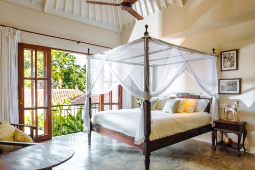 a bedroom with a canopy bed and a balcony at Villas Sabbia in Seminyak