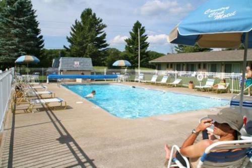 a person sitting in chairs next to a swimming pool at Country Club Motel in Old Forge