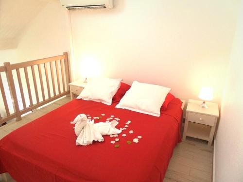 Un dormitorio con una cama roja con dos animales de juguete. en Caraïbes Holidays en Sainte-Anne