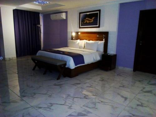 a hotel room with a large bed and a bench at Residence Maryka II in Cotonou