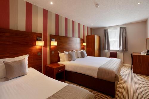 Habitación de hotel con 2 camas y pared a rayas en The Victoria Hotel en Canterbury