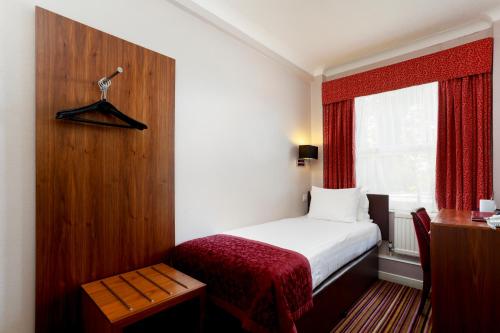 a small bedroom with a bed and a window at The Victoria Hotel in Canterbury