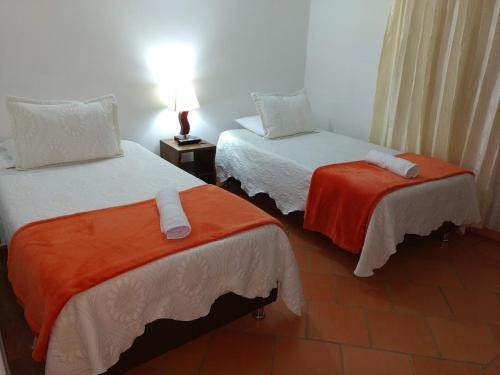 a room with two beds with orange and white sheets at Apartahotel La Gran Familia in Villa de Leyva