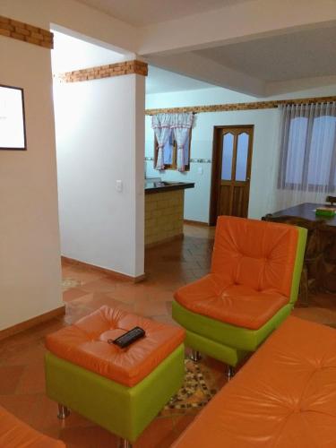 a living room with orange and green chairs and a table at Apartahotel La Gran Familia in Villa de Leyva