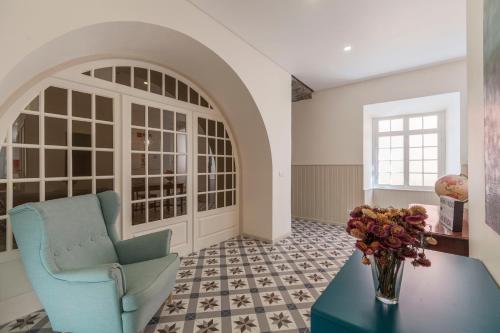 a living room with a chair and a vase of flowers on a table at A Bica Hostel in Ponta Delgada