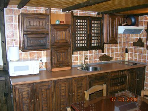 La cuisine est équipée de placards en bois, d'un évier et d'un four micro-ondes. dans l'établissement Rural Bellavista, à Buenavista