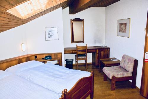 a bedroom with a bed and a desk and a chair at Hotel du Pont in Brig