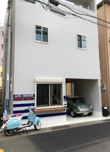 a scooter parked in front of a building with a car at Ano House 女性専用Women's Guesthouse in Kamakura