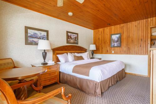 een slaapkamer met een bed, een bureau en een tafel bij The Crossing in Saskatchewan River Crossing