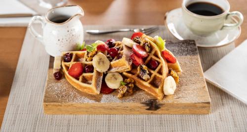 a plate of waffles with fruit and a cup of coffee at Hotel Three Sixty - Adults Only in Ojochal