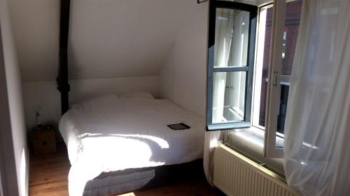 um pequeno quarto com uma cama ao lado de uma janela em Zoetermeer City Center Loft Apartment em Zoetermeer
