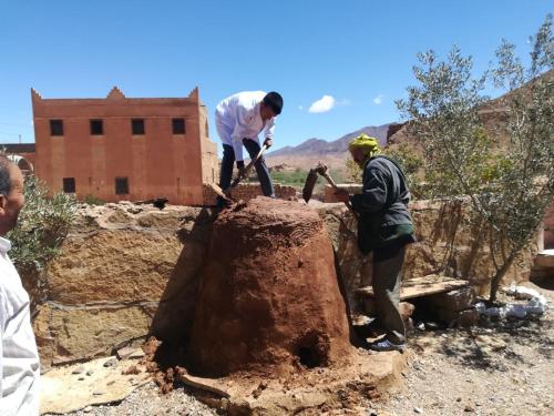 two men are working on a tree stump at Auberge Camping BOUGAFER Tamtetoucht in Tamtetoucht