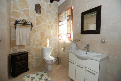 ein Badezimmer mit einem Waschbecken, einem WC und einem Spiegel in der Unterkunft House KIA in Preko