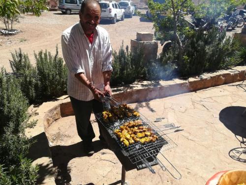 a man is cooking food on a grill at Auberge Camping BOUGAFER Tamtetoucht in Tamtetoucht