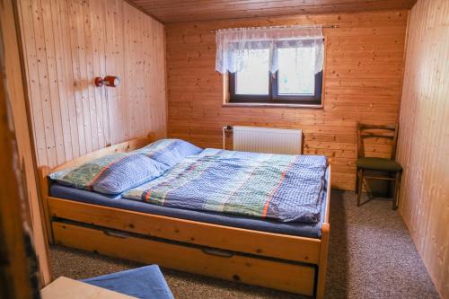 een slaapkamer met een bed in een houten kamer bij Chata Bajama in Bedřichov