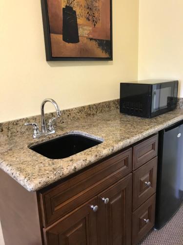 a kitchen counter with a sink and a microwave at Hacienda Motel in Escondido