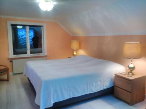 um quarto com uma cama branca e uma janela em Ett hus med 3 sovrum med supersnabba internet fiberanslutningen 1000mb-100mb i Hög, 7 minuter från Hudiksvall em Hudiksvall