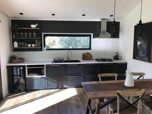 a kitchen with black cabinets and a table and a window at The Retreat in Nicholls Rivulet