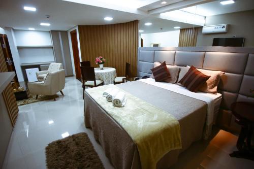 a bedroom with a large bed and a living room at Piloes Palace Hotel in Mineiros