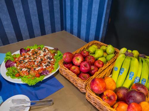 a table with two baskets of fruit and a plate of food at Paradise Resort in Finikounta