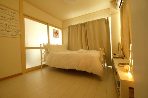 sypialnia z białym łóżkiem i oknem w obiekcie COCO Nakameguro 201 w Tokio