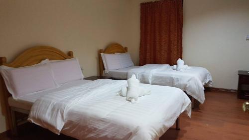 zwei Betten mit weißer Bettwäsche und ausgestopften Tieren darauf in der Unterkunft Hotel 45 Beach Resort in Bauang
