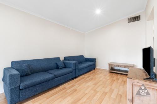 a living room with a blue couch and a tv at Central Caravan Park in Perth