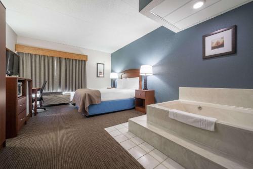 a hotel room with a bed and a bath tub at AmericInn by Wyndham Hutchinson in Hutchinson