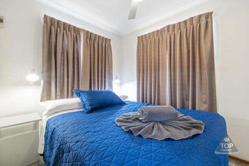 um quarto com uma cama com lençóis azuis e uma janela em Central Caravan Park em Perth