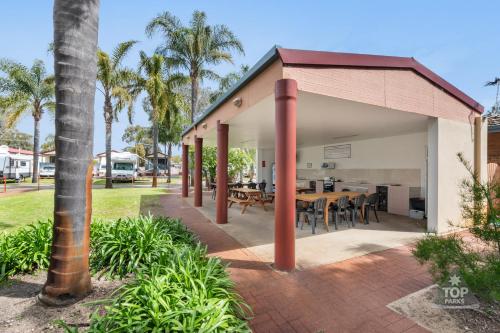 a pavilion with a table and chairs and palm trees at Central Caravan Park in Perth