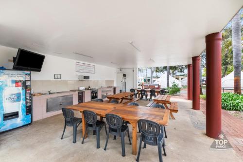 a restaurant with tables and chairs and a kitchen at Central Caravan Park in Perth