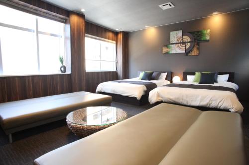 ein Zimmer mit 2 Betten und einem Sofa darin in der Unterkunft Tanimachi 4chome 4F in Osaka