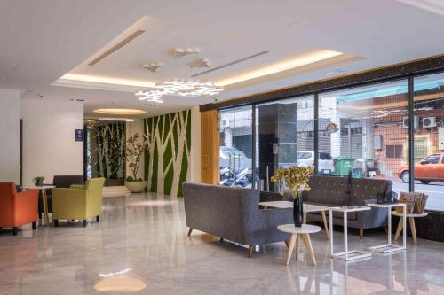 a lobby with chairs and tables and windows at 衿后禾居民生館 Good Hotel Minsheng in Kaohsiung