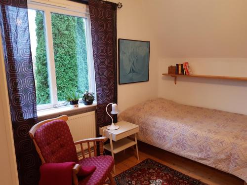 um quarto com uma cama, uma cadeira e uma janela em Perenner på bakgården em Motala